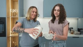 Mother and teenage daughter happily making pancakes together in modern kitchen - Powered by Shutterstock - Get 15% off with code: PIKWIZARD15