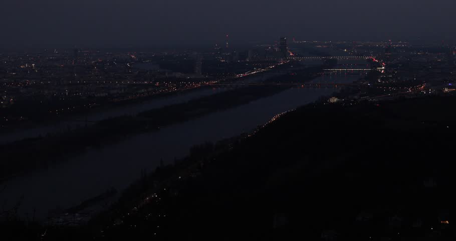 Night aerial view of Vienna city skyline. Danube river bridges and reflections. Relatively high noise level due to the night filming circumstances. 
