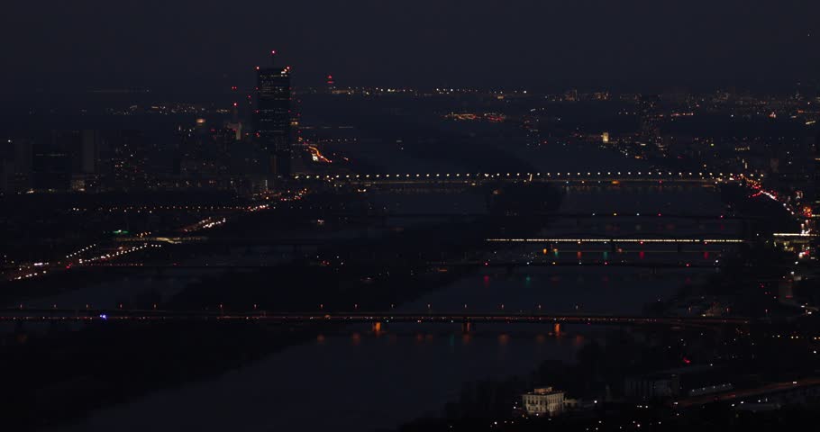 Night aerial view of Vienna city skyline. Danube river bridges and reflections. Relatively high noise level due to the night filming circumstances. 