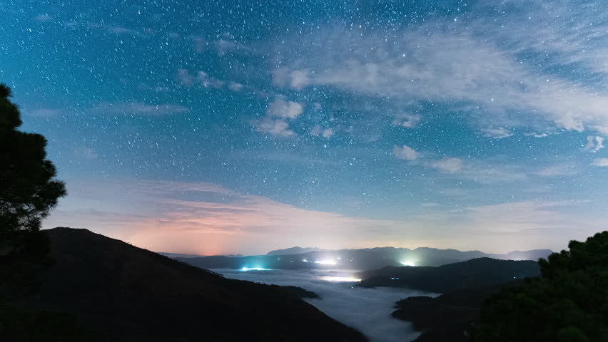 Night sky stars with trails above mountainous landscape, time lapse