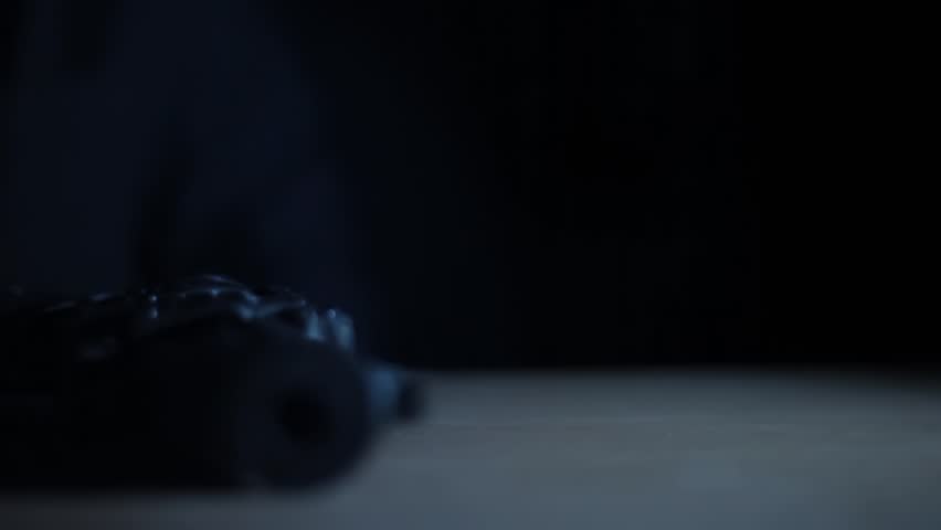 Close-Up of a Man Picking Up a Gun from a Table — Dramatic Cinematic Shot with Creative Lighting