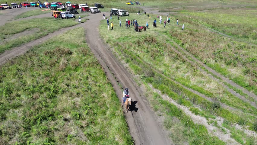 Aerial view of green mountain slope, winding riverbed, parking area, cloudy sky, scenic landscape, nature, outdoors, remote, travel, adventure, panorama.