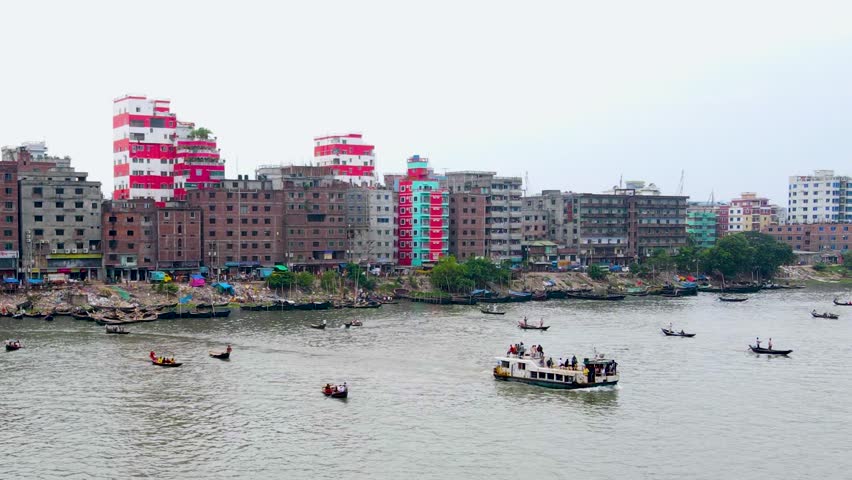 Aerial: Boats with passenger on Buriganga river in Dhaka, Bangladesh during the day. Establishing drone shot