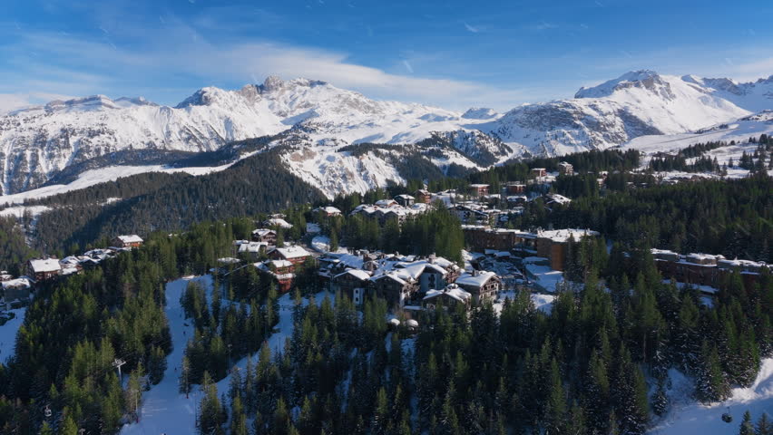 This aerial view showcases the snowcovered mountains and the charming village of Courchevel in the French Alps, captivating adventurers seeking exploration and outdoor experiences