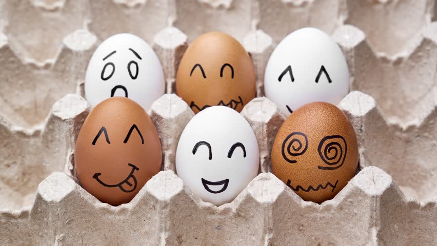 Eggs with funny faces in box. Happy, angry, sad, surprised faces on white and brown eggs. Stop motion. Funny cartoon faces. Food concept. Close-up of hen eggs. 4K, UHD