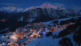 Experience the breathtaking beauty of Courchevel at night from above, where snowcovered mountains blend with dazzling lights, creating a vibrant and captivating nightscape that enchants all - Powered by Shutterstock - Get 15% off with code: PIKWIZARD15