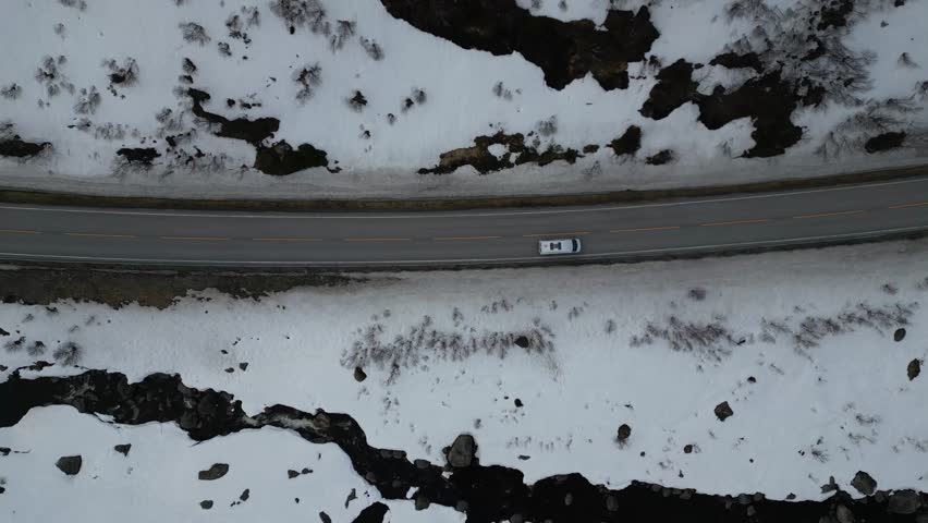 Top shot of white car passing by on a winding road near the Olden Norway waterfall in Briksdalsbreen, Stryn municipality in Vestland county.