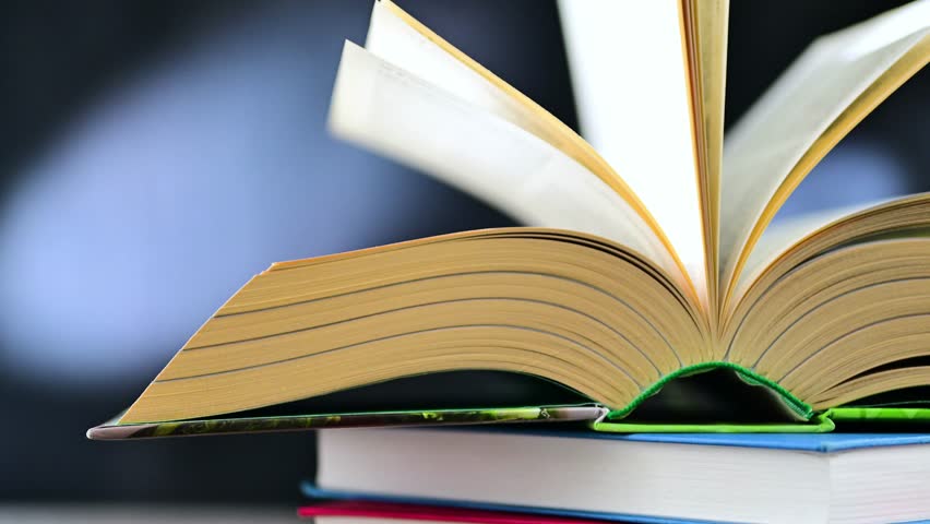 An open book lying on a stack of other books