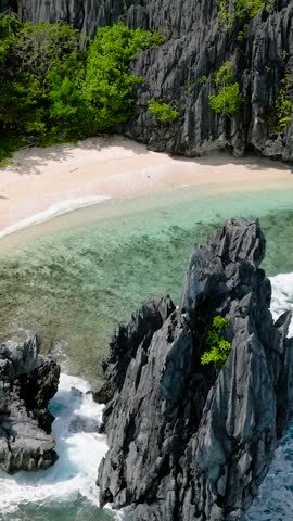 Waves crashing on white sand beach in Matinloc Island. El Nido, Palawan. Philippines. Vertical view.