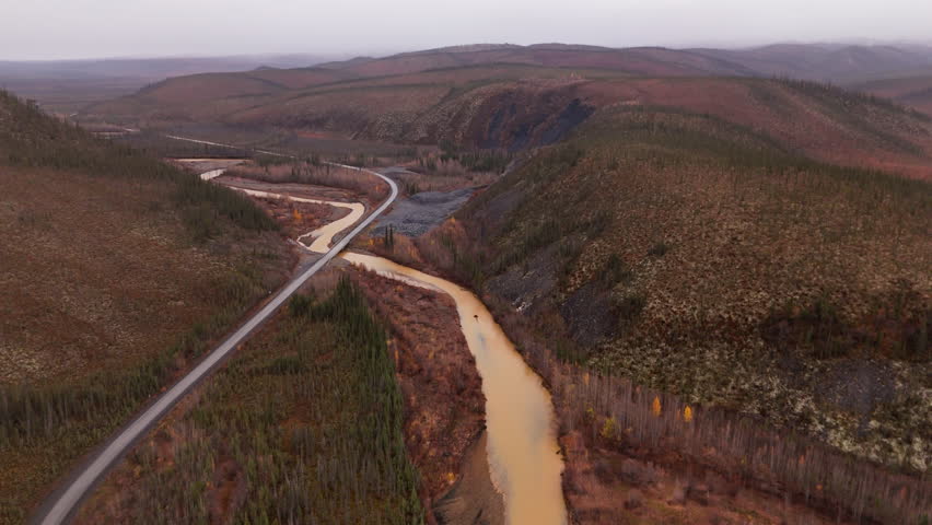 Dempster Highway Across Ogilvie River In Yukon Territory, Northwestern Canada. aerial pullback shot