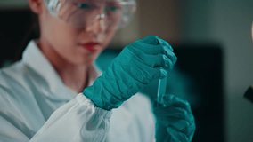 Female scientist in lab coat analyzing green liquid substance within sterile laboratory environment, examining test tube with precision and professional concentration - Powered by Shutterstock - Get 15% off with code: PIKWIZARD15