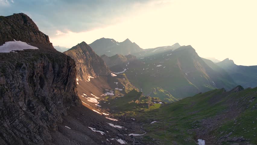 Aerial of alpine mountains in Switzerland in the Grindelwald valley at sunset. Dramatic storm clouds over high peaks