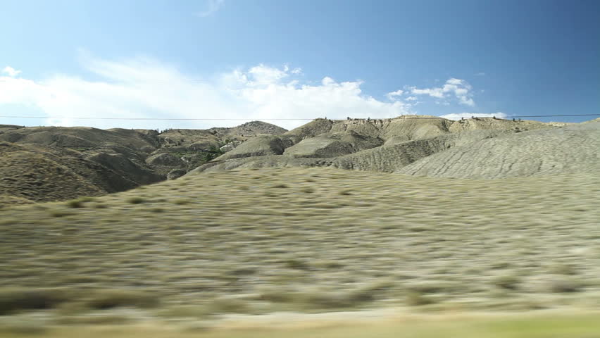 Driving view of Wyoming landscape with scrubland in foreground and the foothills