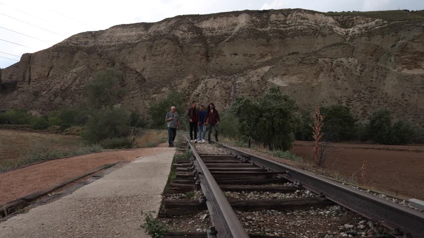 Four musicians walk on railroad tracks, enjoying the scenery and each other