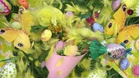 Yellow feathers blown by soft wind from the top over a colorful Easter festive decoration with tulips, decorated eggs, butterflies, paper umbrellas, and yellow feathers on a daisy-themed background. - Powered by Shutterstock - Get 15% off with code: PIKWIZARD15