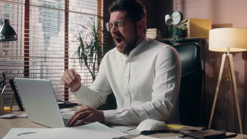 Stressed Caucasian guy manager executive male tired businessman worker man ceo leader broker working online in office typing laptop yawn exhaustion problem drinking coffee energy beverage cup business