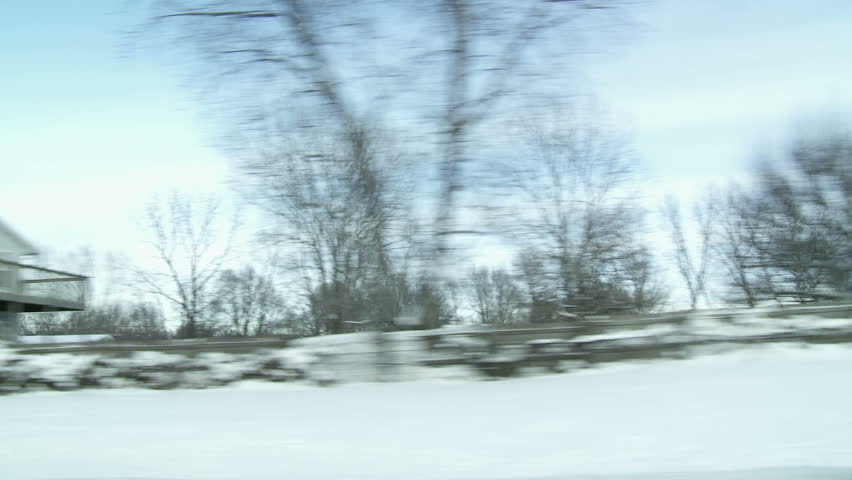 View from car window while driving past snow-covered farmland in the Mid West,