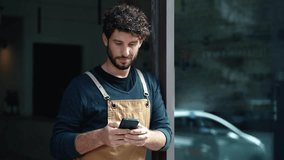 Video of handsome waiter using smartphone while leaning on the coffee shop door - Powered by Shutterstock - Get 15% off with code: PIKWIZARD15