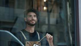 Video of handsome young waiter hanging the open sign on a glass door in the pastry shop - Powered by Shutterstock - Get 15% off with code: PIKWIZARD15