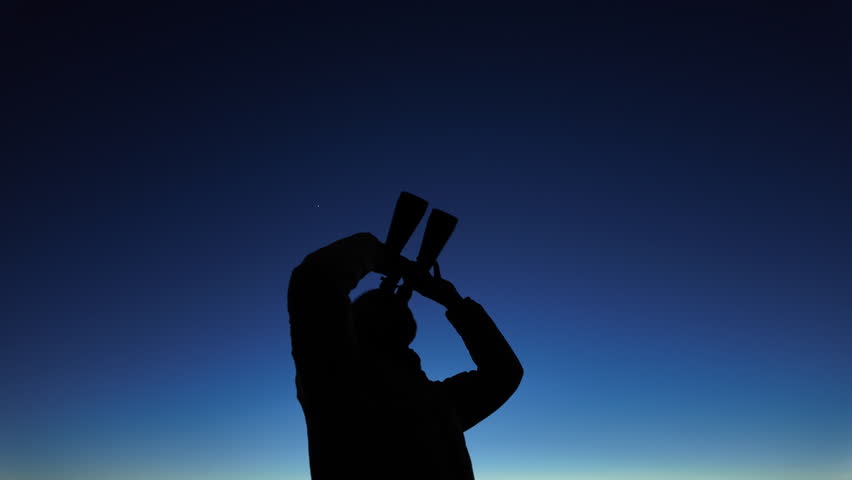 Silhouette of a man with binoculars and countryside under the stars and Moonlight.