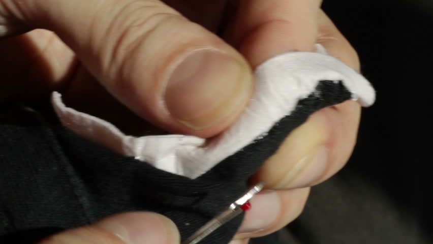 Removing white cotton stitches from a piece of clothing. Clip recorded with a