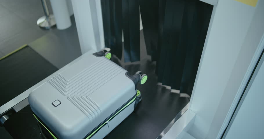 Security Checkpoint in Modern Airport Terminal: Passenger's Suitcase Moving on Conveyor Belt from Advanced Metal Detector X-ray Scanner. Luggage Scanning Procedure before Boarding Flight. High Angle.