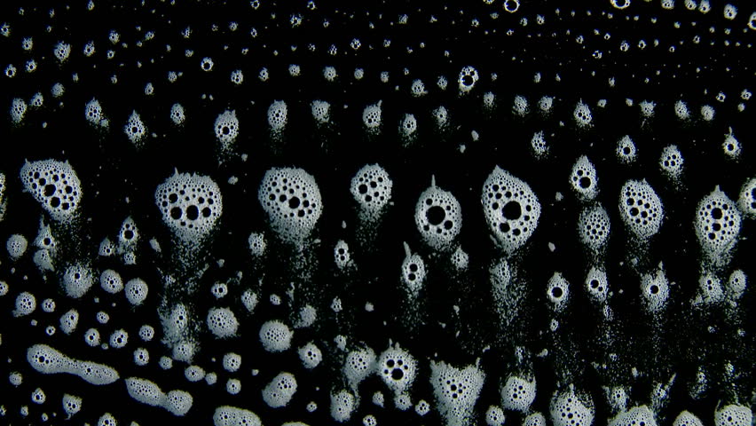 White foam bubbles slowly running downwards against a black background.