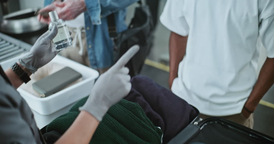Security Checkpoint in Airport Terminal: Close Up of TSA Worker Inspecting Luggage of Passenger before Boarding Flight, Finding and Confiscates Liquid. People, Travelers During Screening Procedures.