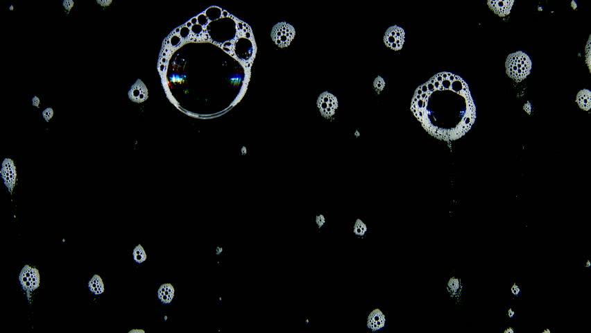 White foam with bigger bubbles running downwards against a black background.