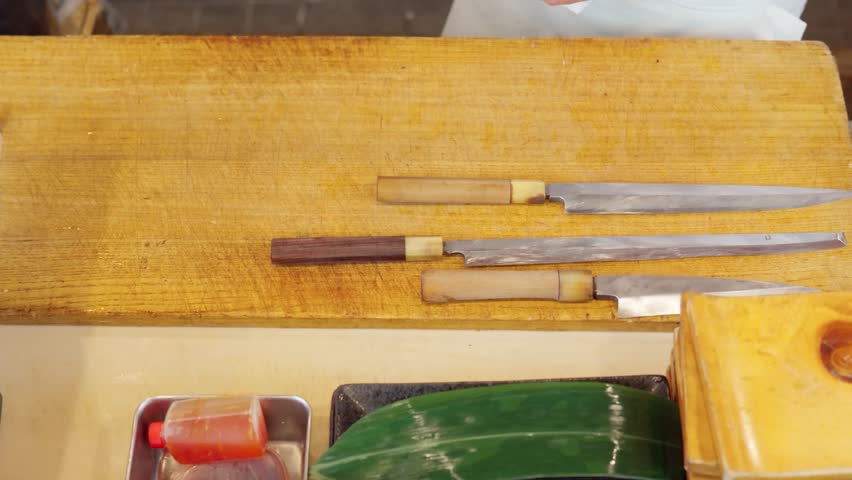 The hands of a sushi chef wiping the cutting board