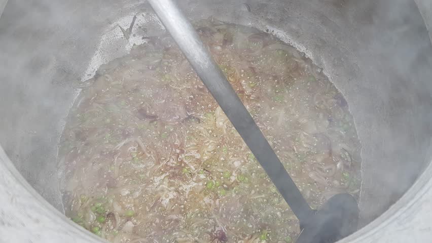 Cooking Meat with Onions and Green Spices in a Large Pot