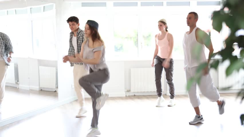 Active young guys and girls practicing hip-hop reject step in training hall during dancing classes. High quality 4k footage