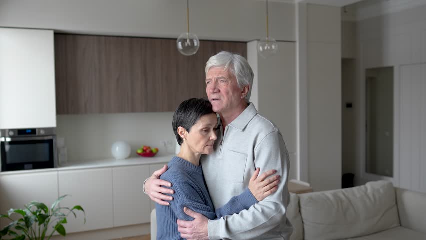 Depressed tearful anxious mature man lovingly embraces tired wife, offering support. Emotional crisis in family, comforting each other, helping spouse cope with confusion and grief, lost and sorrow