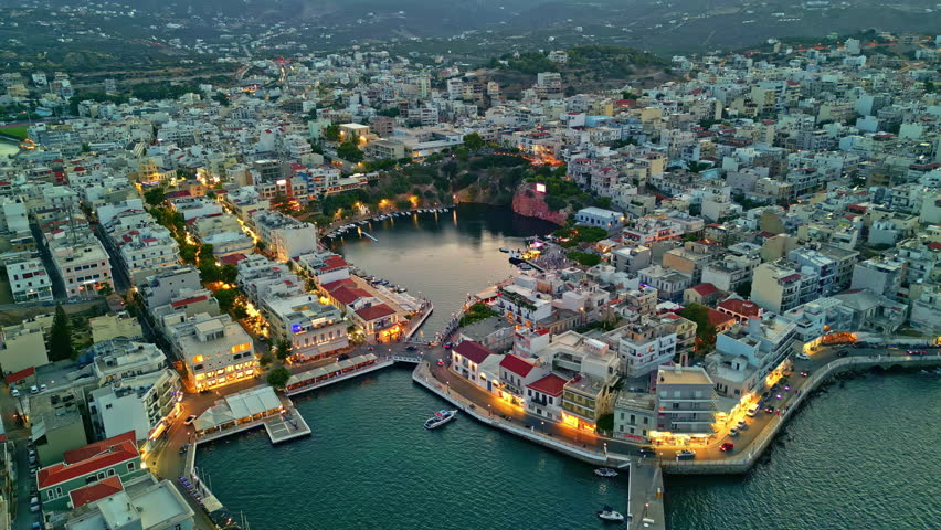 Drone view, coastal Crete island city Agios Nikolaos at dusk, Greece vacation