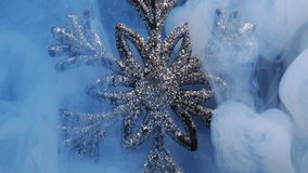 Winter magic. Christmas snowflake. Blue color ink water vapor cloud revealing sparkling glitter silver ornament on dark abstract background. - Powered by Shutterstock - Get 15% off with code: PIKWIZARD15