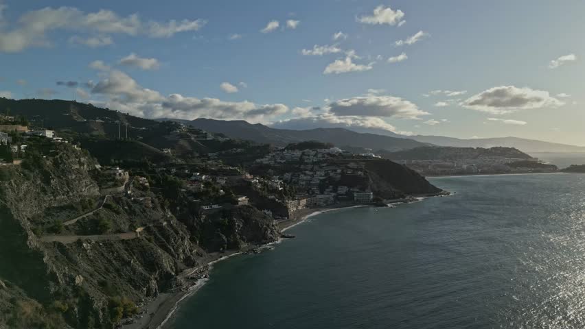 Push in drone shot of Almunecar Coast during the day with Mediterranean Sea and cityscape in Granada, Spain