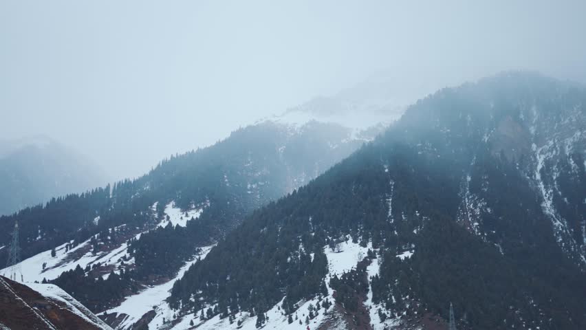 4K Slow motion shot of Himalayan mountain peak covered by stormy clouds during the winter season and a little snowfall in front of snowy Himalayas as seen from Sonmarg in Jammu and Kashmir, India.