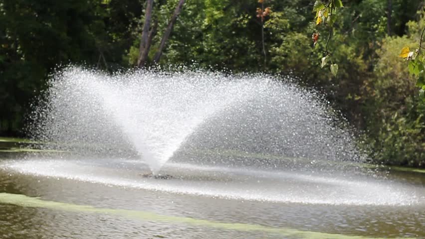 A nice fountain in the middle of a lake with calm water and smooth sprays.