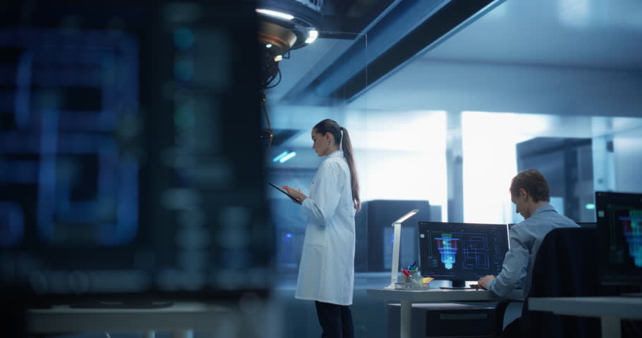 Female Science Student Using a Tablet to Monitor the Work of a Quantum Computer in a Technology Institute, Focusing on Data, Compute and Hardware. Futuristic Space in an Advanced Technological Office