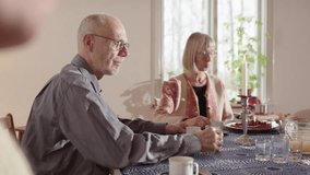 Mature balding man with glasses sips drink at table at Swedish family fika - Powered by Shutterstock - Get 15% off with code: PIKWIZARD15