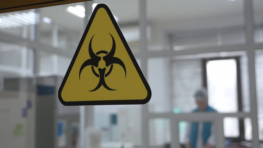 Yellow triangular chemical hazard sign on the glass door in the laboratory. A modern laboratory for analysis and testing.