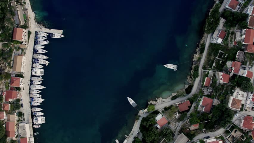 Aerial top view of boats and yachts in marina from above. Yacht parking,Summer sea cruise on ship at green mountains island. White yacht . View from above of white boat on deep blue water.