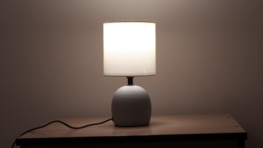 People is turning on and off modern night table lamp switch. Warm lighting for bedside lamp for reading books. Close up.