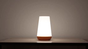 Man is adjusting Modern color changing led lamp. Eco rechargeable bedside lamp with remote control for cozy atmosphere at home. 4k footage. - Powered by Shutterstock - Get 15% off with code: PIKWIZARD15