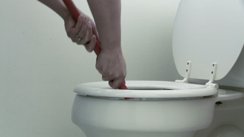 Using a plunger in an attempt to unclog a toilet. Dolly move in this clip.
