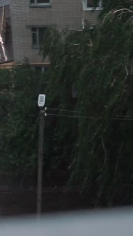 View from the window of extreme weather with rain and thunderstorm. City with high-rise buildings of Soviet panel architecture. Dark atmosphere with clouds and lightning, sky timelapse