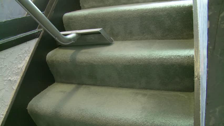 Detail of a steam wand being used to clean the carpet on a staircase.