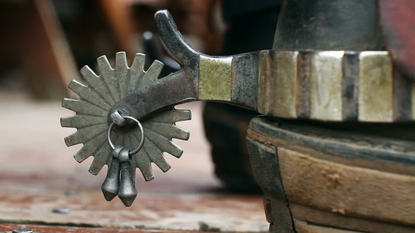 Detail of a working cowboy's spurs with jingles. His hand reaches down and spins
