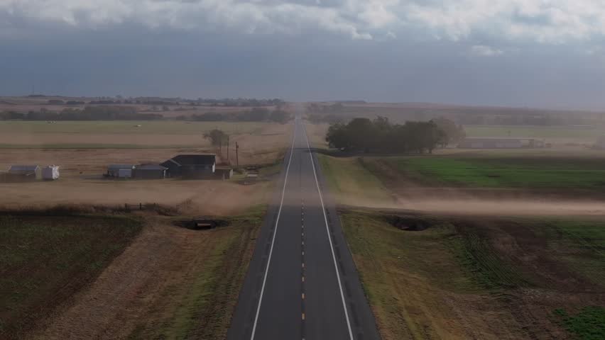 A wide view of an empty Oklahoma highway with dust blowing across the road