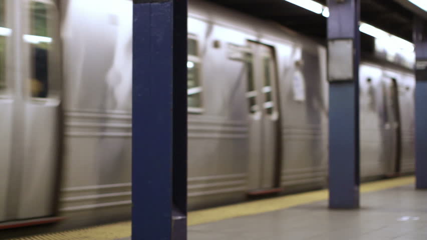 Subway train departs from platform in Manhattan, New York. Wide shot with